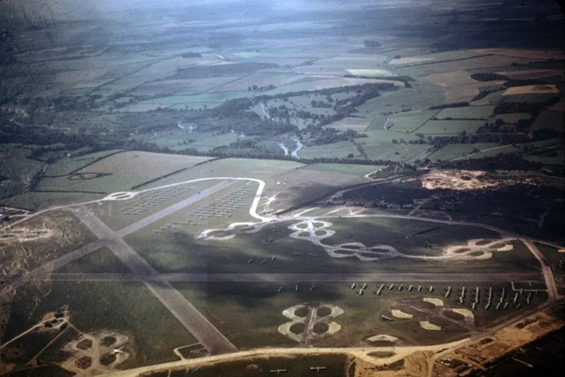 Aerial colour photo of Chilbolton airfield in September 1944, with rows of aircraft and gliders parked beside the runways